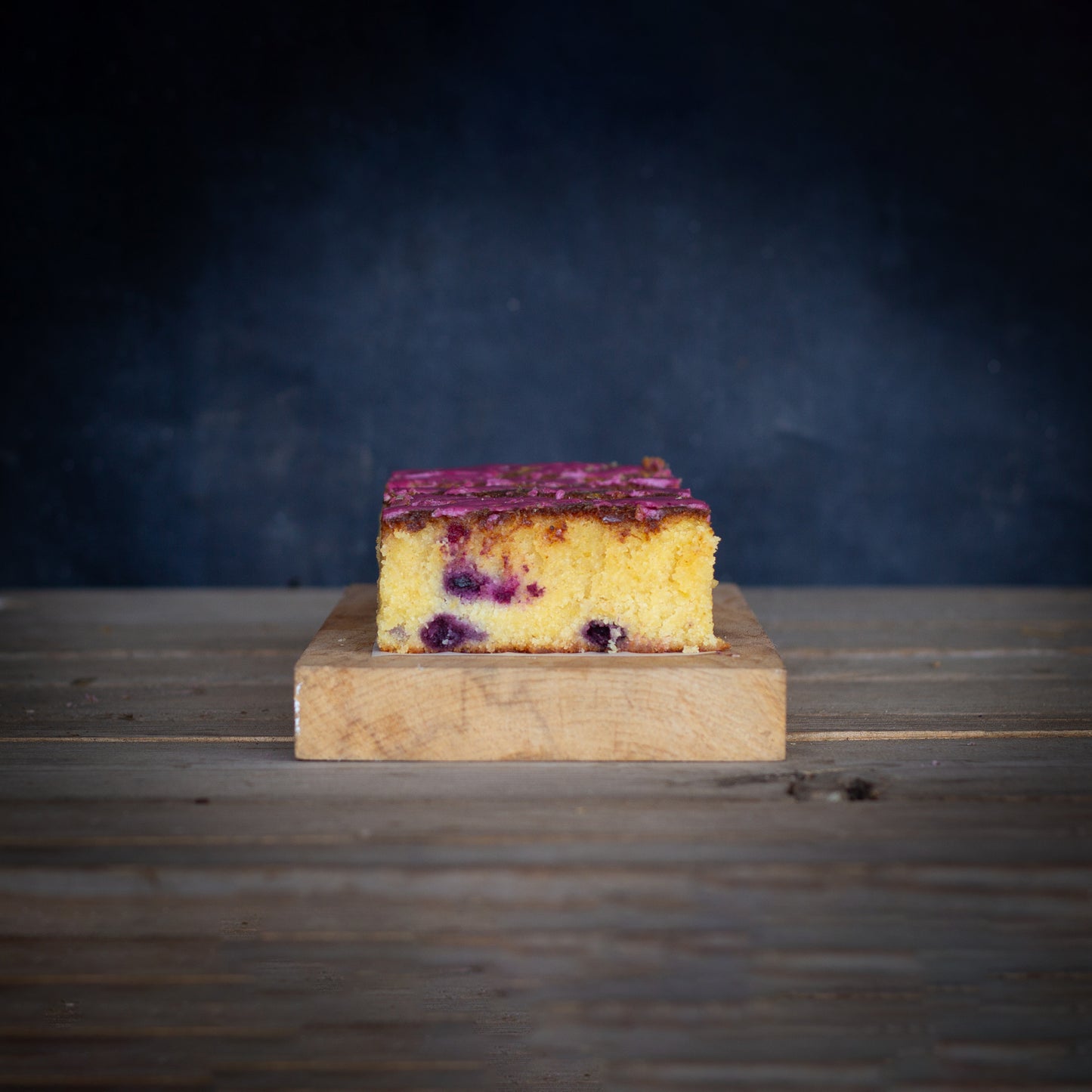 Slice of cake on a wooden board with a dark background