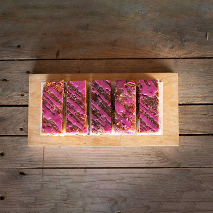 Wooden board with pink and white dessert slices on a wooden surface